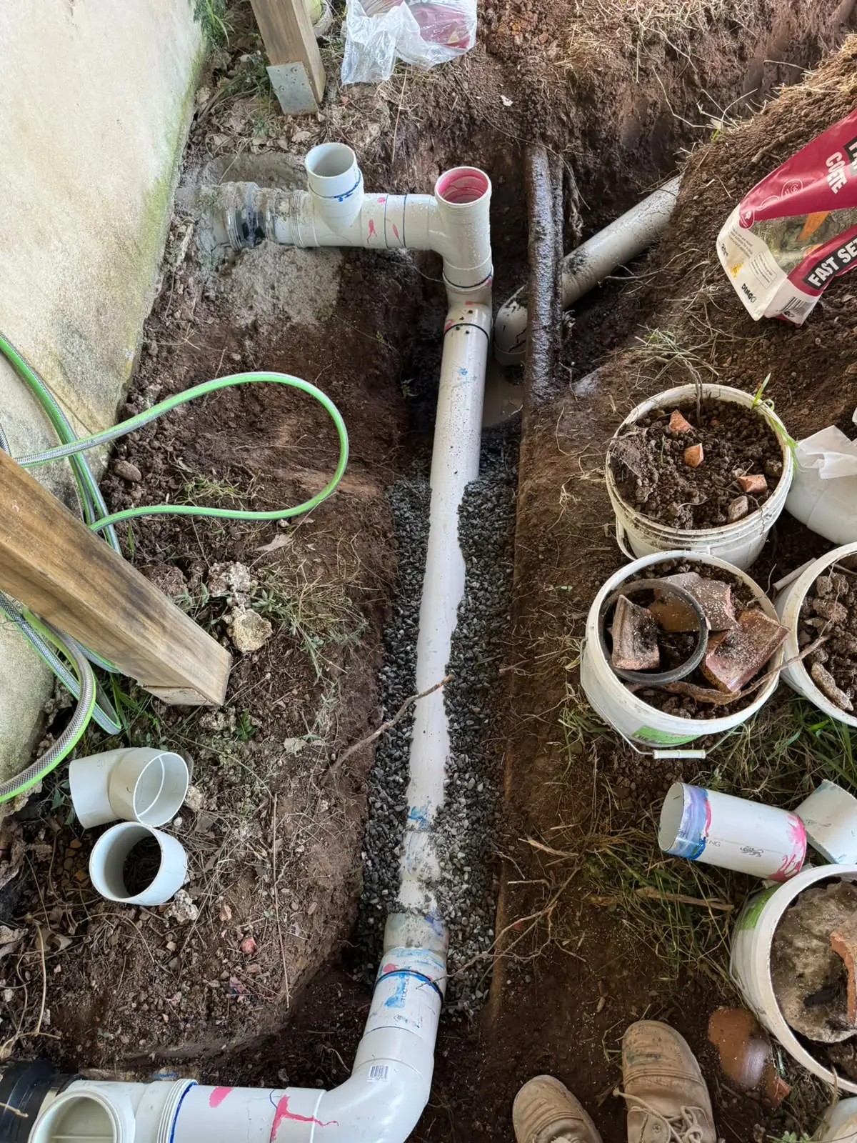 New PVC drainage pipe installed in an excavated garden trench