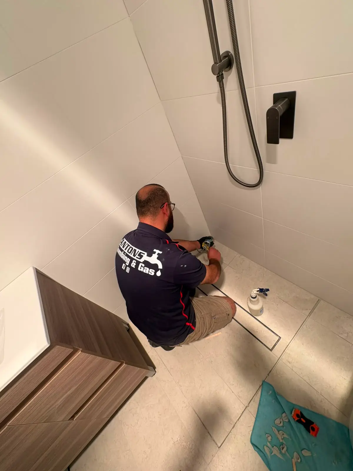 Antons plumber completing plumbing work inside a tiled shower
