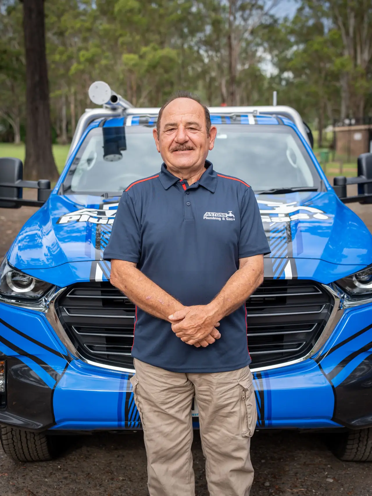 Antons plumber standing in front of a blue plumbing service vehicle